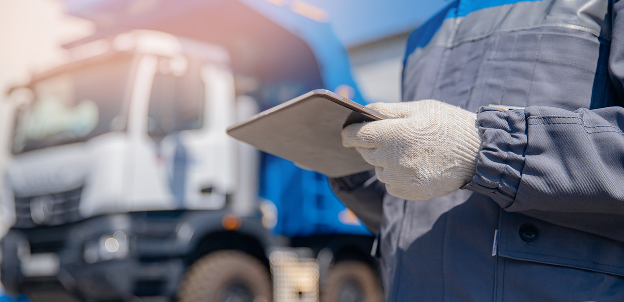 Travailleur utilisant une tablette devant un camion de collecte de déchets.