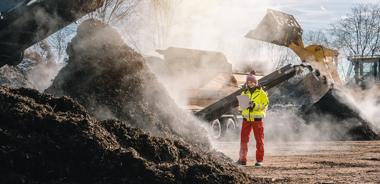Travailleuse inspectant un site de compostage, montrant les solutions de BioService pour les odeurs industrielles.
